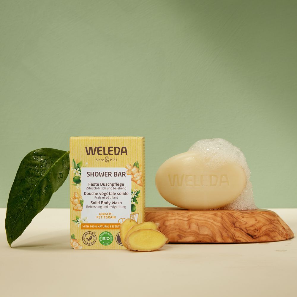 Product en verpakking op houten plank. Zeep met schuim. Verpakking met "WELEDA"-logo en productnaam. Groene achtergrond.