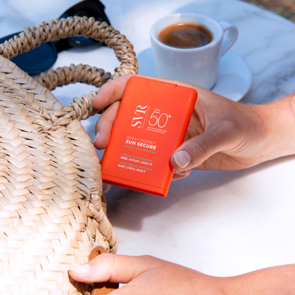 Persoon die oranje SVR SUN SECURE Pocket Spray in een strandtas stopt.