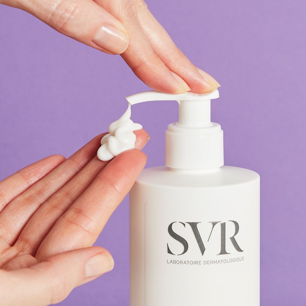 Gros plan d'une main pressant de la crème d'une pompe. Marque: SVR. Produit: XERIAL 10.