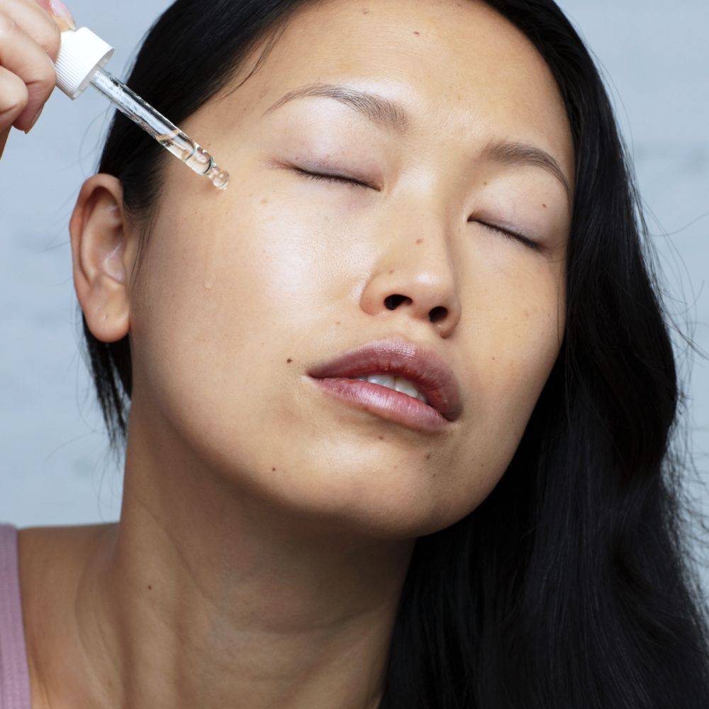 Vrouw brengt olie aan op haar gezicht met een pipet. Ogen gesloten. Opschrift: SVR, Huile de Nuit Sensifine.