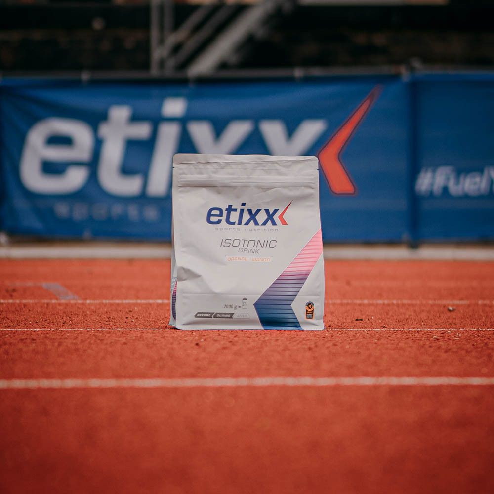 Etixx Isotonic Drink Orange/Mango. Emballage sur piste rouge. Logo et nom du produit visibles. Avec certification.