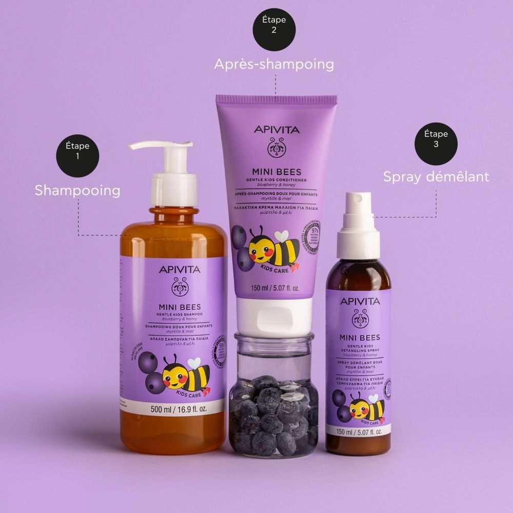 Trois produits: shampooing, conditionneur et spray. Tous avec illustrations d'abeilles et myrtilles. Sur fond violet.