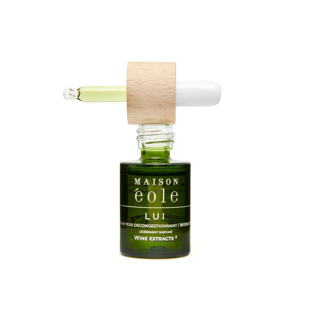 Grüne Glasflasche mit Holzdeckel und Pipette. Pipette mit Flüssigkeit. Aufschrift: Maison Éole, Lui, Sérum Yeux Décongestionnant Intensité.