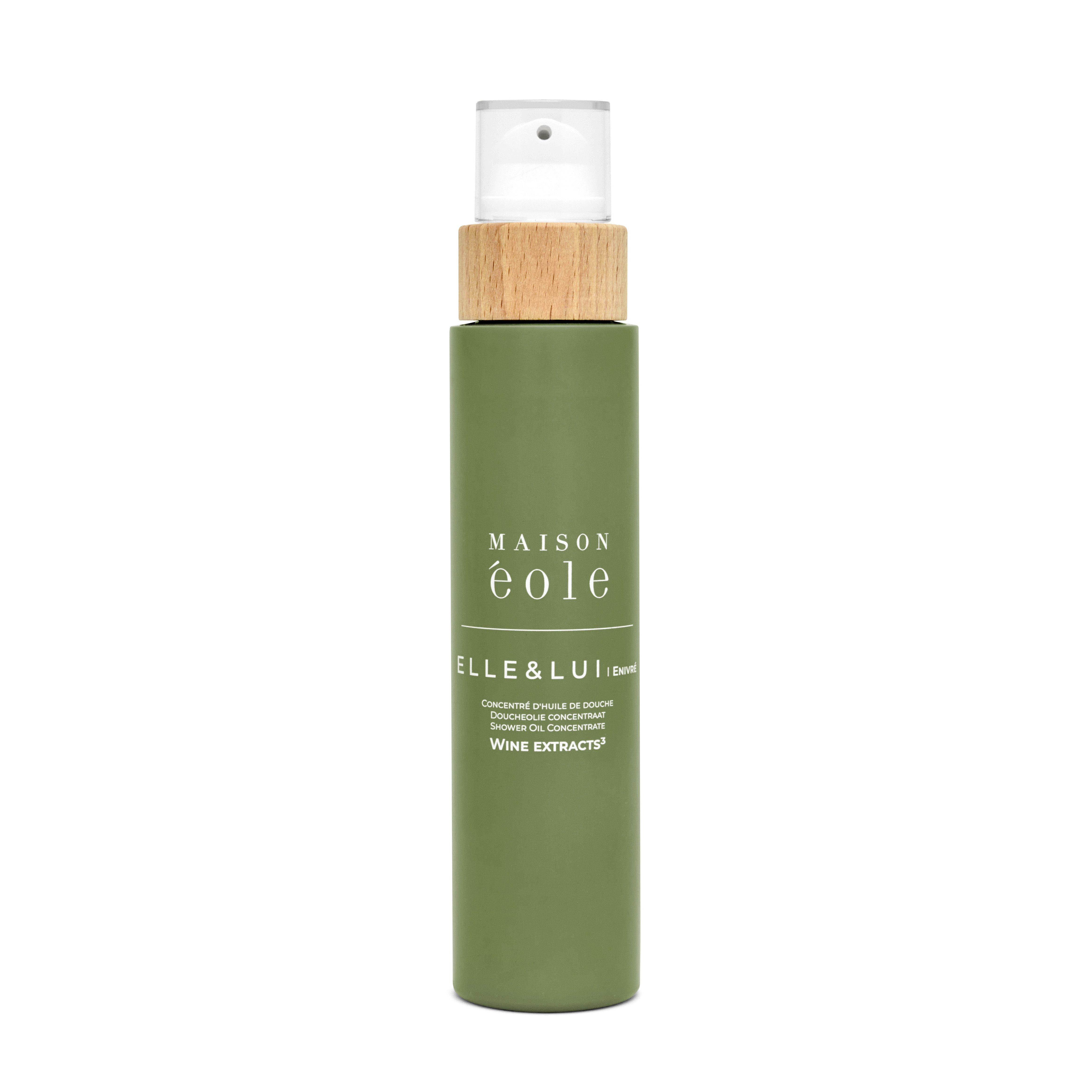 Grüne Flasche mit Sprühkopf und Holzdeckel. Aufschrift: Maison Éole, Elle & Lui, Concentré d'Huile de Douche.
