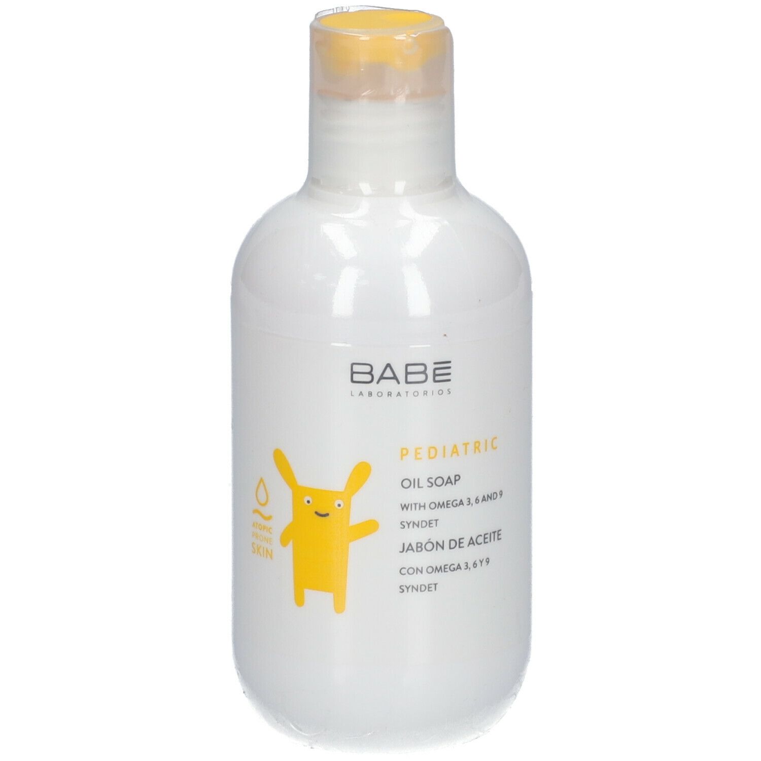 Weiße Flasche mit gelbem Verschluss. Aufschrift: BABÉ, PEDIATRIC OIL SOAP. Gelbe Cartoon-Figur.