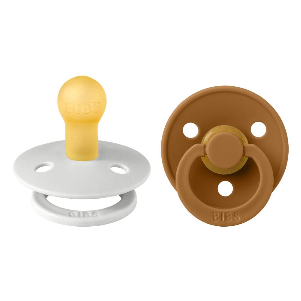 Zwei Schnuller, einer weiß, einer braun. Beide mit rundem Sauger und Ring. Marke BIBS.