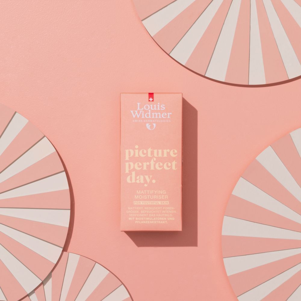 Productverpakking op roze achtergrond met decoratie. Doos met tekst: picture perfect day. Mattifying Moisturiser.