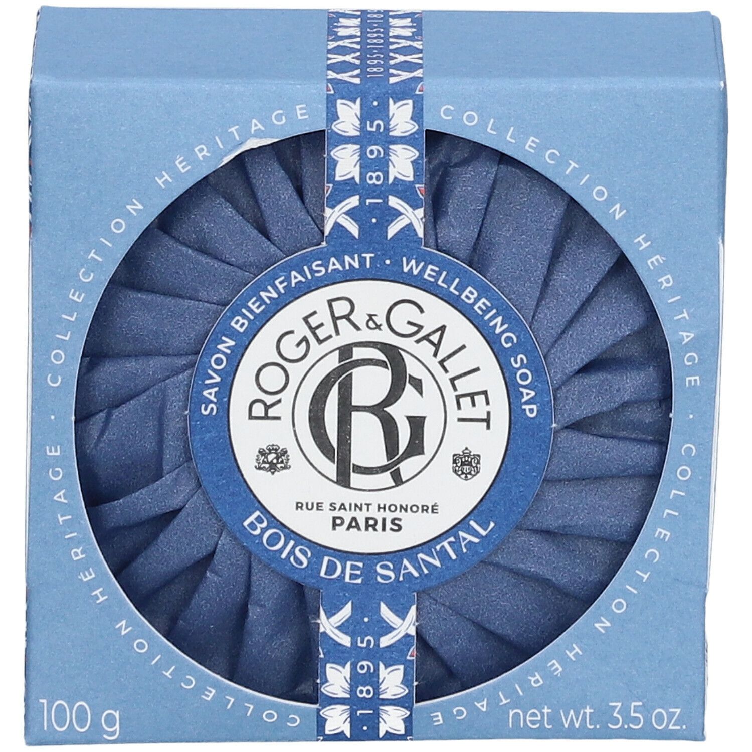 Blaue Seife in einer blauen Schachtel. Die Schachtel hat ein rundes Fenster, durch das die Seife sichtbar ist. Auf der Verpackung steht "Roger & Gallet".