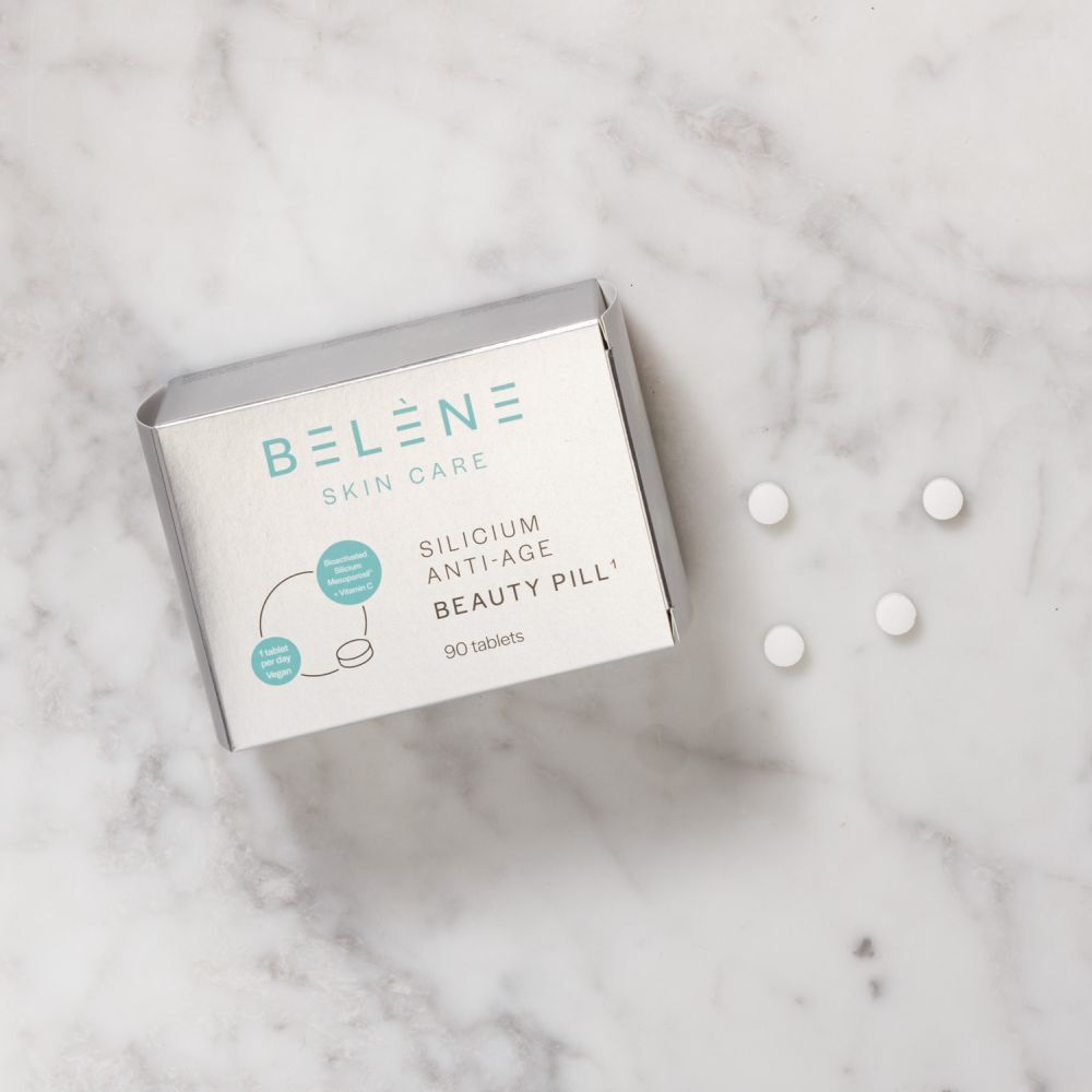 Zilveren doos BELÈNE Skin Care en tabletten op marmer. Opschrift: Silicium Anti-Age Beauty Pill.