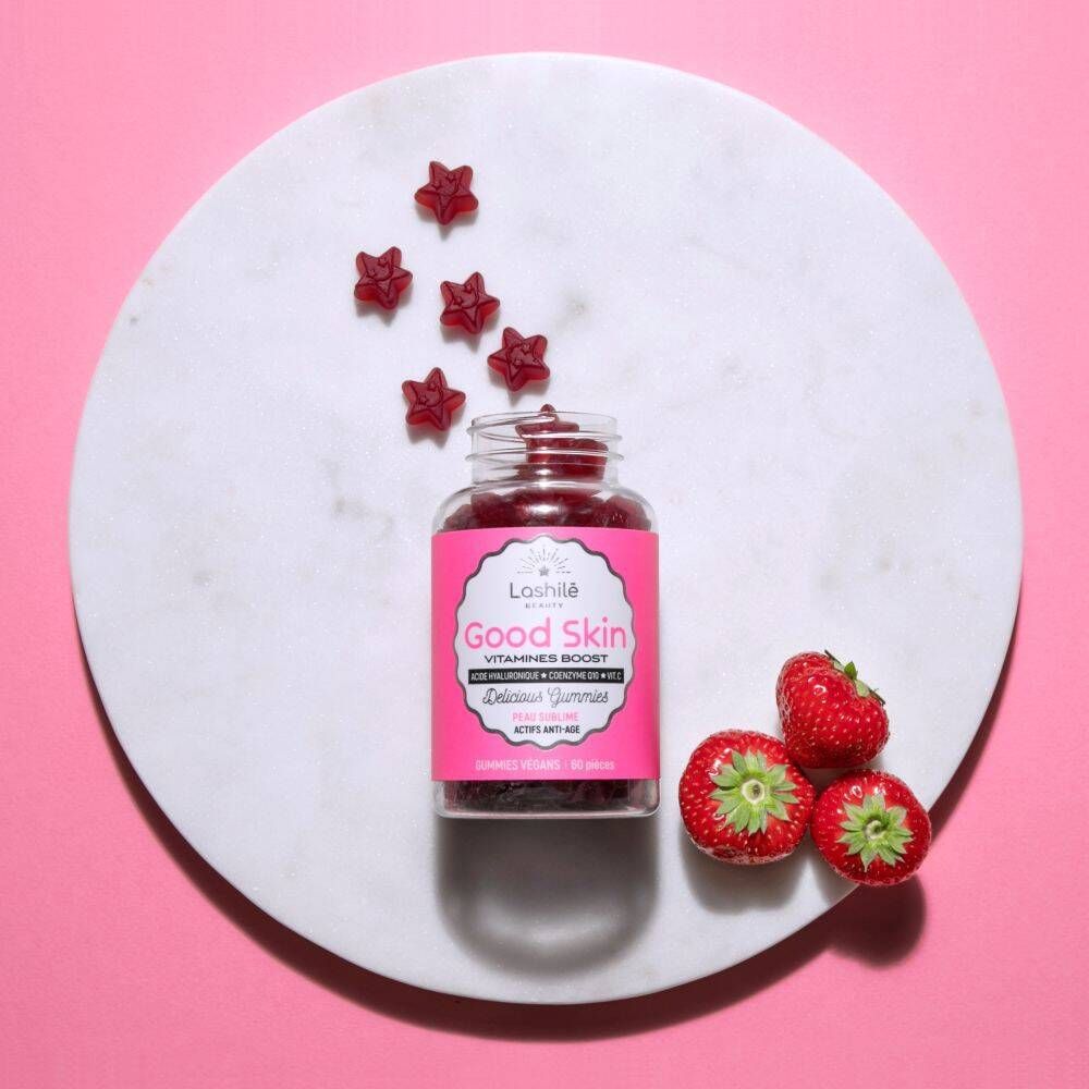 Gommes, flacon et fraises sur assiette blanche. Fond rose.