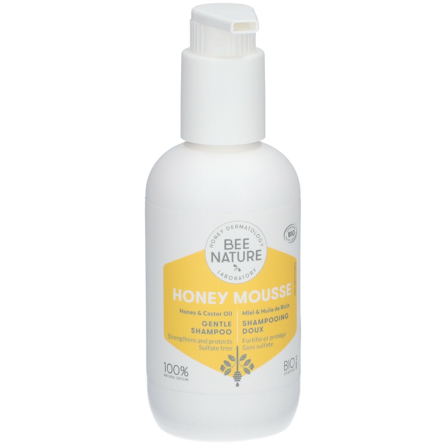 Flacon blanc avec pompe. Étiquette jaune avec texte: Honey Mousse, Gentle Shampoo. Certification Bio.