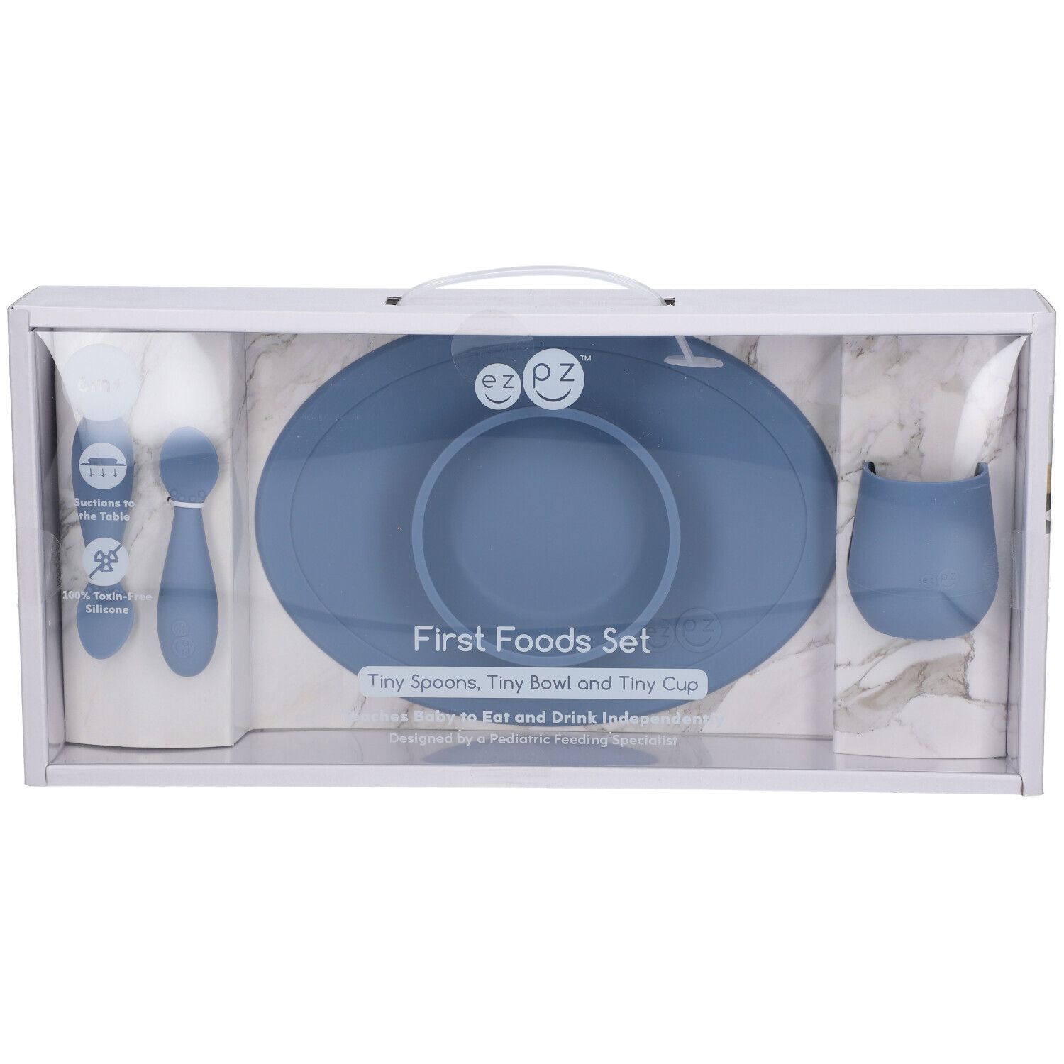 EzPz First Foods Set: Blaue Silikon-Lätzchen, Löffel, Schüssel und Becher im Karton.