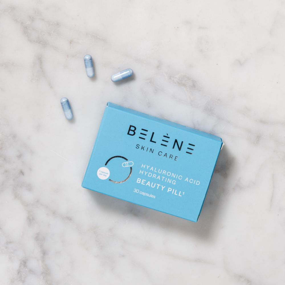 Boîte bleu clair "BELENE SKIN CARE" et trois gélules sur marbre. Texte: "ACIDE HYALURONIQUE HYDRATANT BEAUTY PILL".