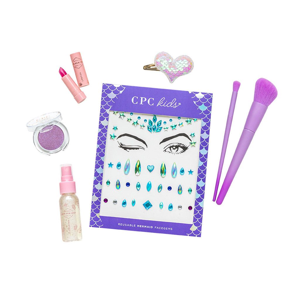 Set de maquillage avec fard à paupières, rouge à lèvres, pinceaux, vaporisateur, autocollants et barrette. Sur fond blanc.