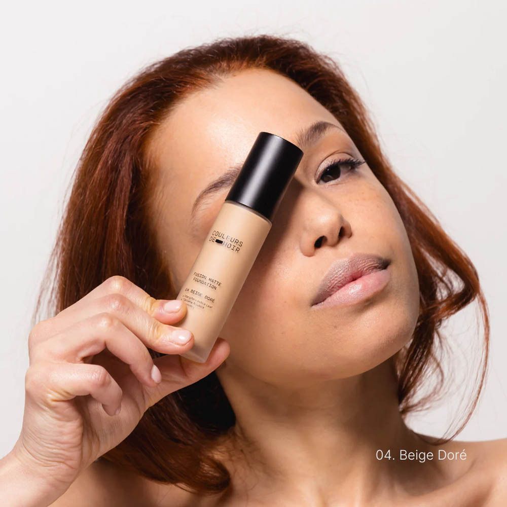 Vrouw houdt foundationfles vast. Op de fles staat 'Couleurs de Noir' en 'Fusion Matte Foundation 04'.