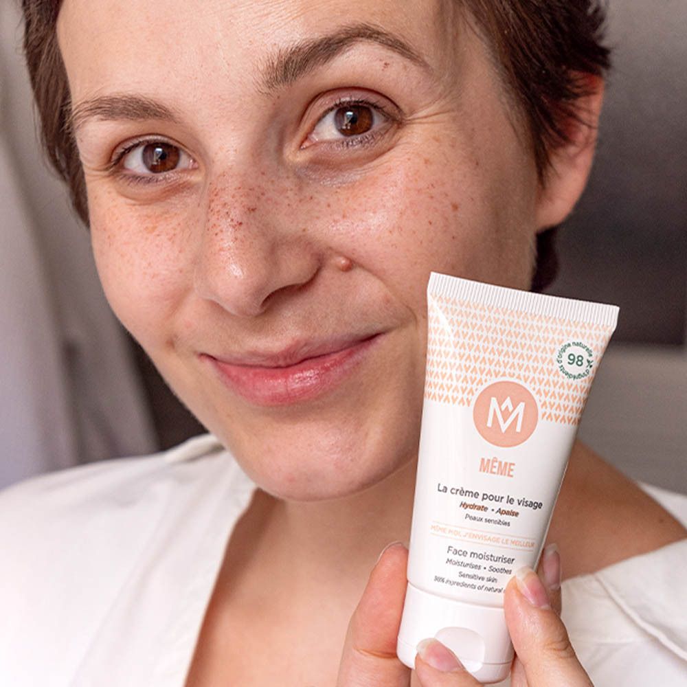 Femme tenant un tube de crème. Inscription : MÊME, La crème pour le visage. 98% d'ingrédients d'origine naturelle.