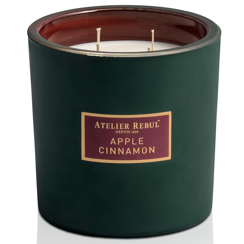 Bougie verte avec bord rouge et étiquette "ATELIER REBUL Apple Cinnamon". Deux mèches visibles.