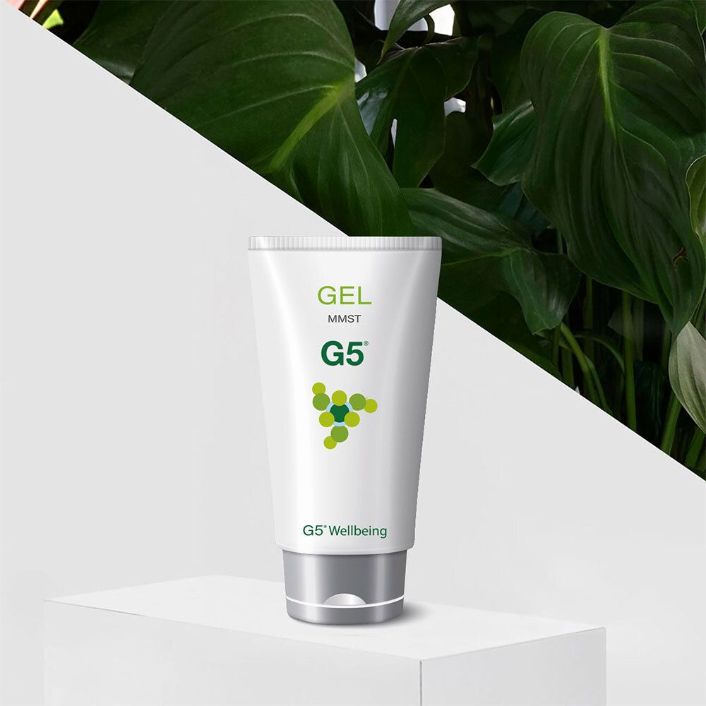 Witte tube met groen logo en tekst. Opschrift: GEL MMST G5 Wellbeing. Zwarte dop. Geplaatst voor groene planten.