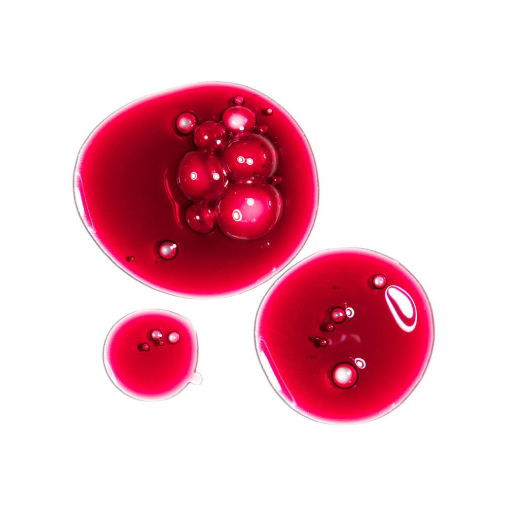Gros plan de gouttes de liquide rouge. Certaines gouttes ont des bulles.