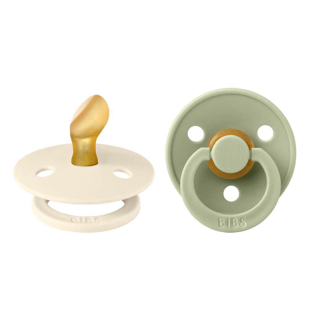 Zwei Schnuller: Elfenbein und Grün. Runde Form, anatomischer Sauger, Ring mit BIBS-Logo.