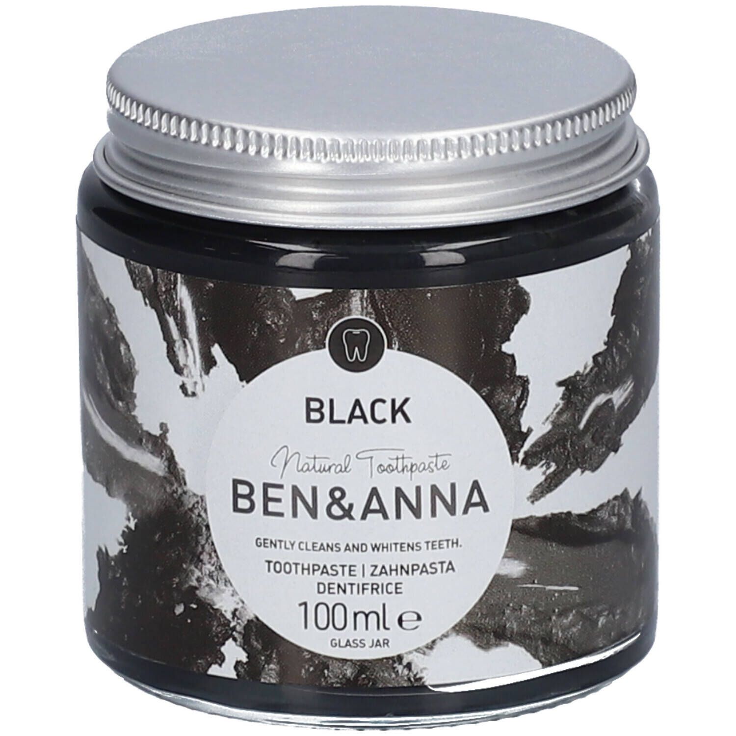 Schwarze Zahnpasta in einem Glas. Deckel silberfarben. Aufkleber mit Produktinformationen und Markenname.