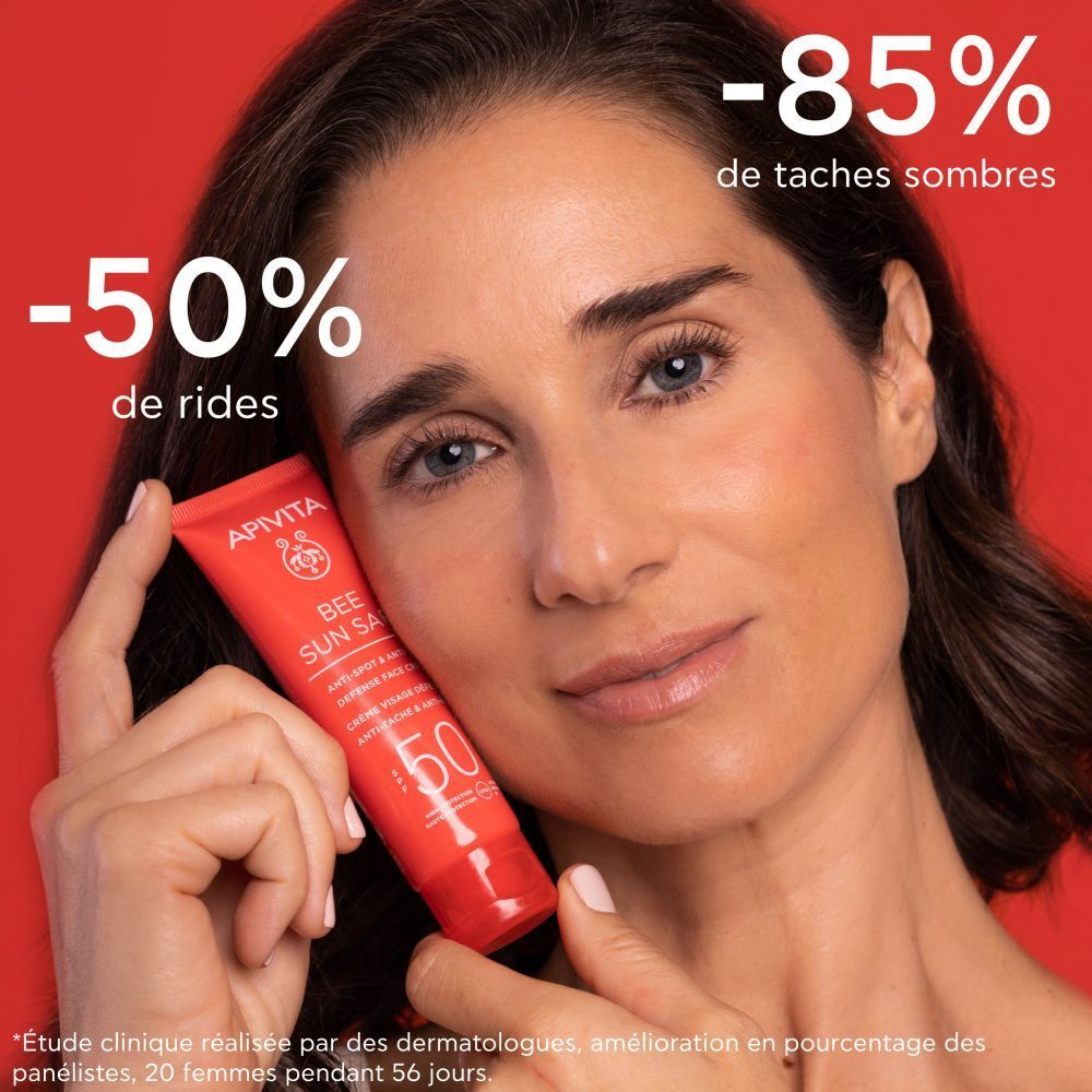 Femme avec produit. Tube rouge: Apivita Bee Sun Safe. Réduit les rides et les taches.