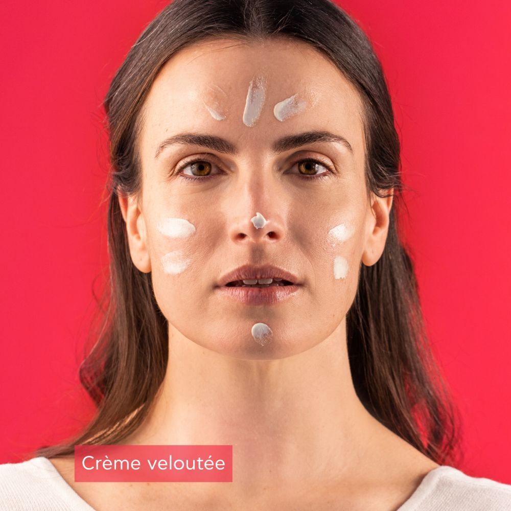 Femme avec crème sur le visage. Tube rouge: Apivita Bee Sun Safe. Crème veloutée.