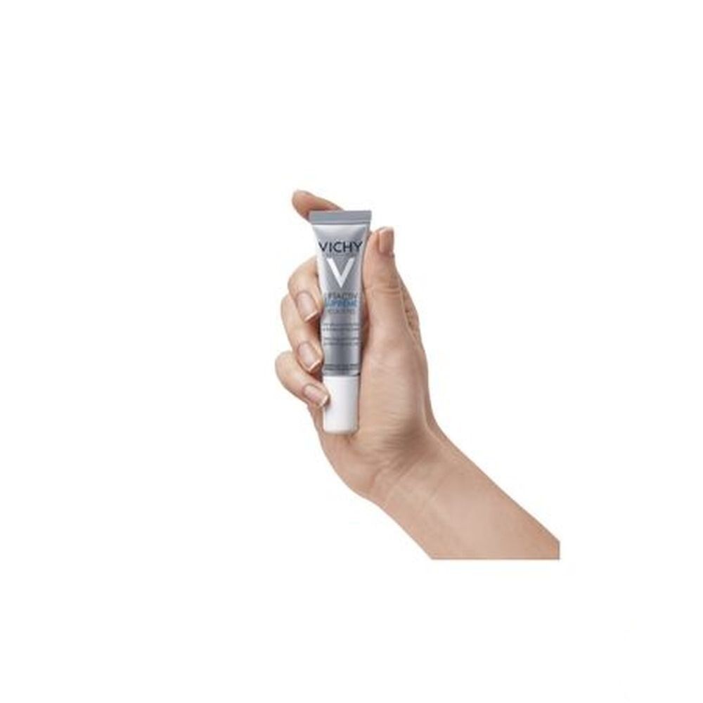 Main tenant un tube de crème pour les yeux Vichy Liftactiv. Tube gris, bouchon blanc. Vue du produit.