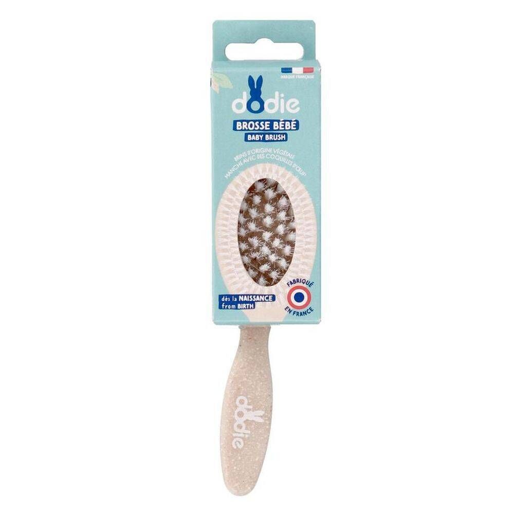 Brosse bébé Dodie dans son emballage. Tête ovale avec poils clairs et foncés. Manche avec logo. Fabriqué en France.