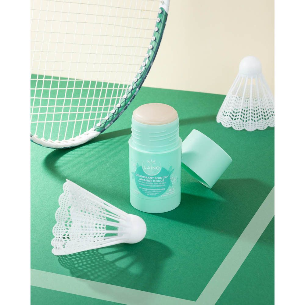 Stick de déodorant et couvercle sur fond vert. Raquette de badminton et volants dans l'image.