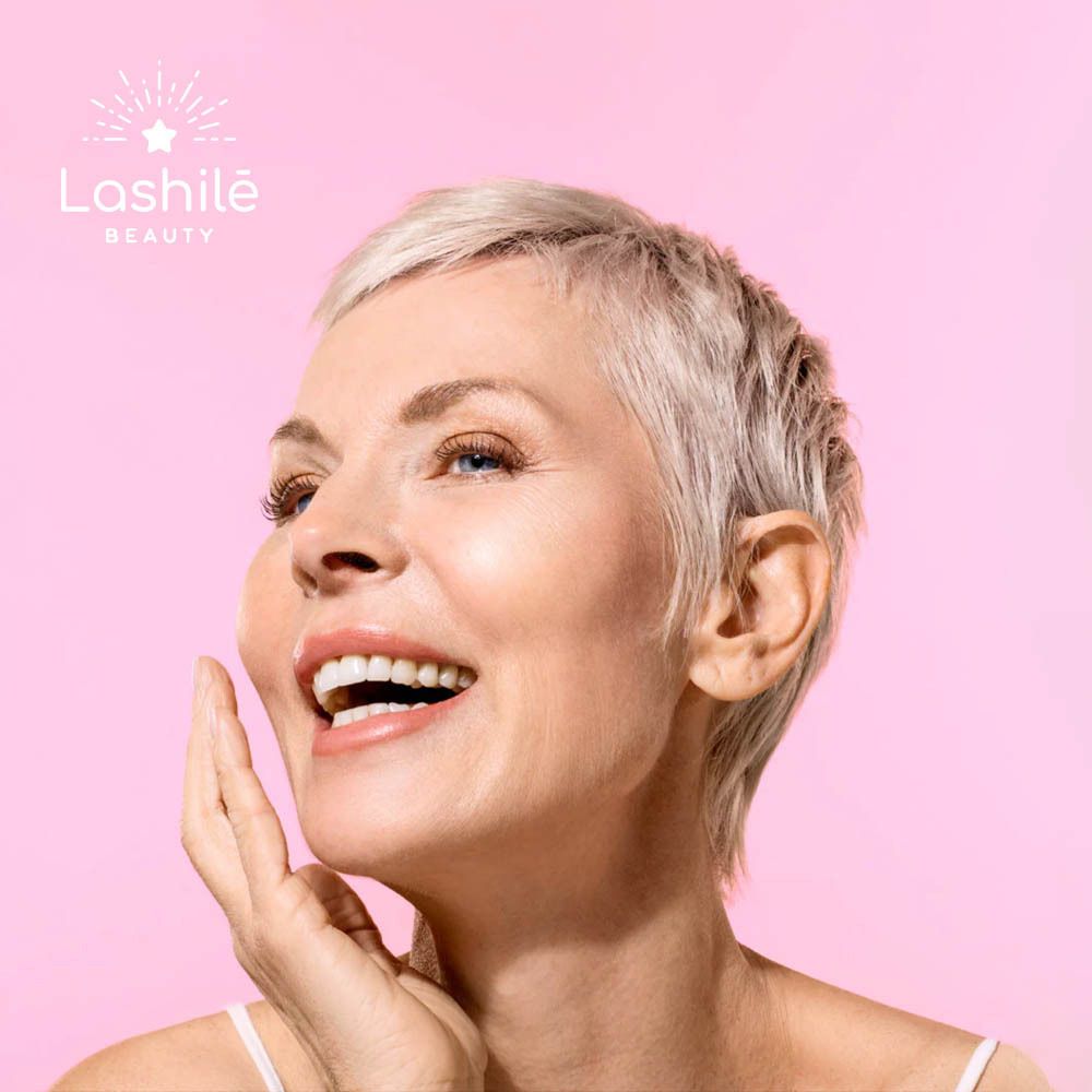 Femme souriante, touchant son visage. Fond rose.