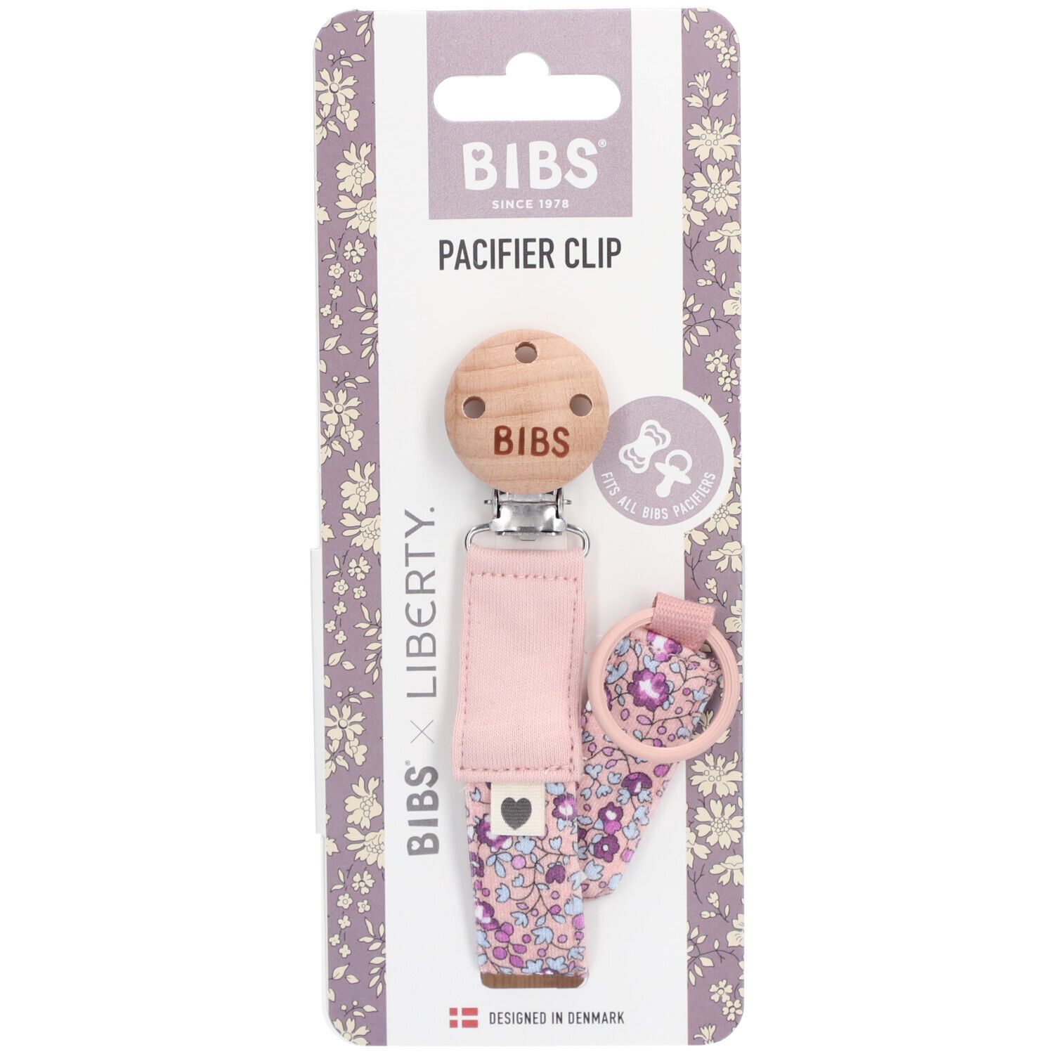 Verpackung mit Schnullerhalter. Holzclip mit BIBS-Logo. Rosa Stoffband mit Blumenmuster. BIBS x Liberty.