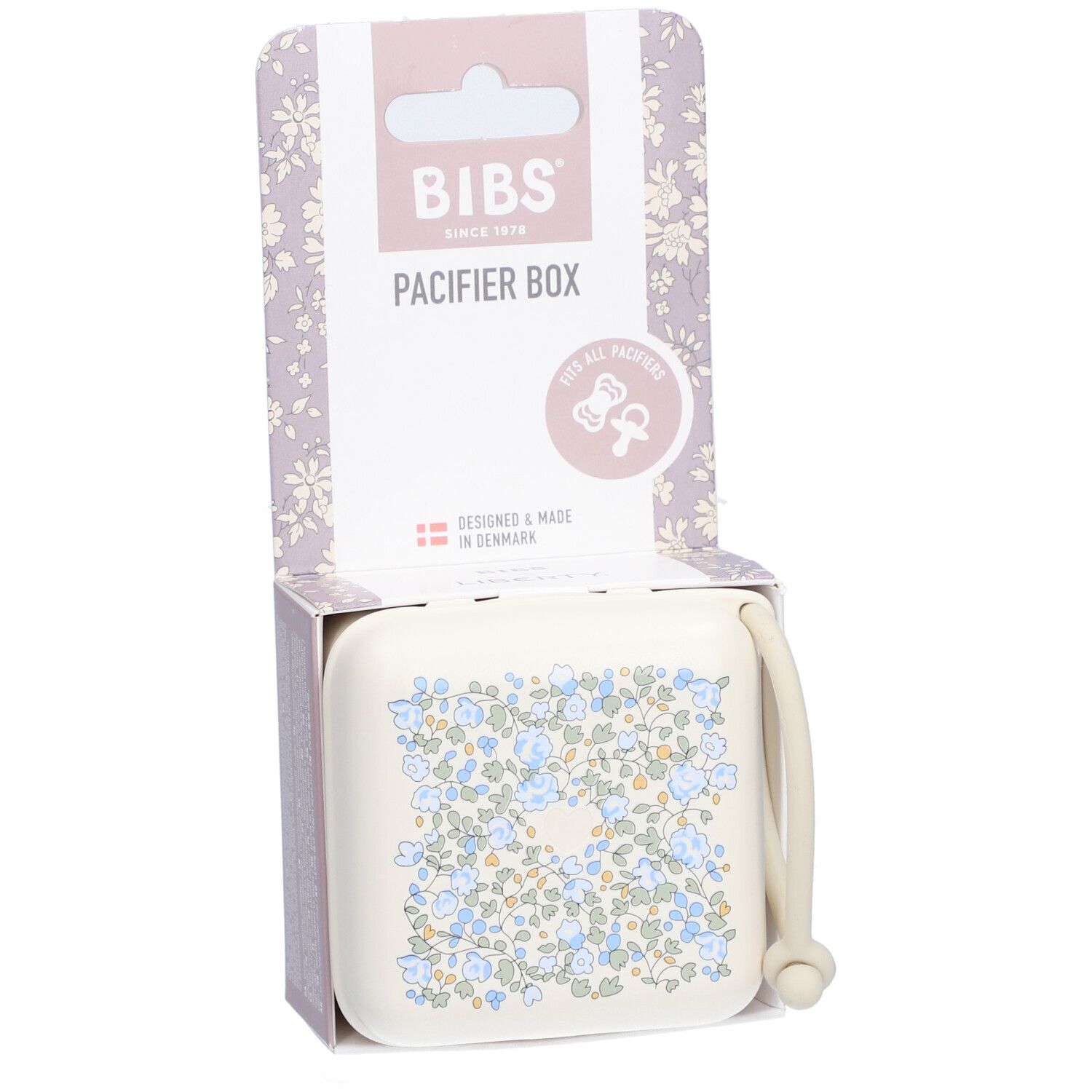 BIBS Schnullerbox in Verpackung. Beige Box mit blauem Blumenmuster. Deckel mit Griff. Verpackung mit Logo.