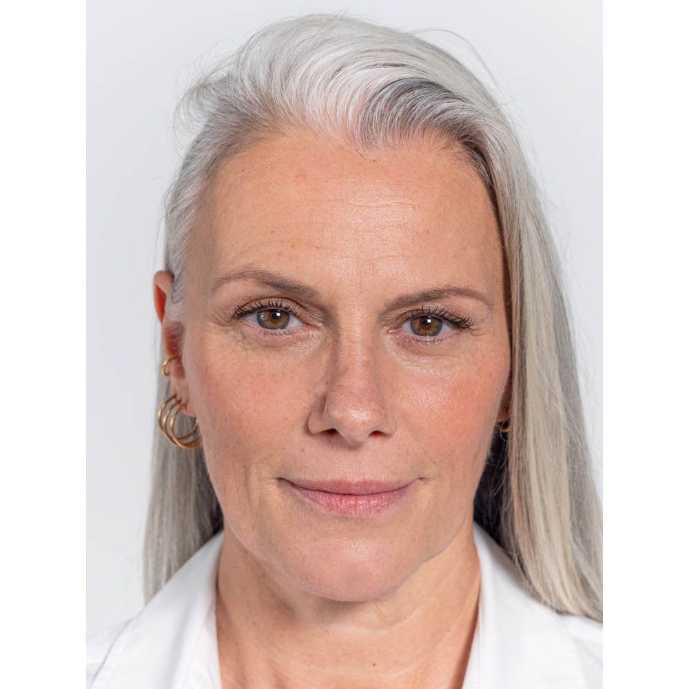Portrait d'une femme aux cheveux gris. Elle porte du mascara.