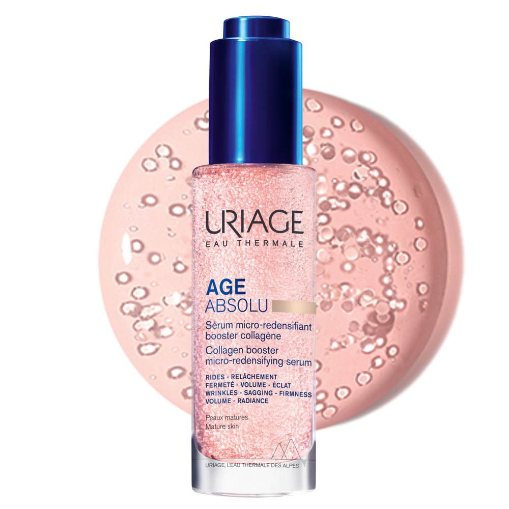 Flacon de sérum rose à bouchon bleu. Inscription: Uriage, Age Absolu. Fond rose avec bulles.