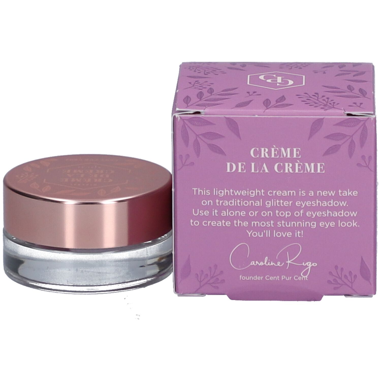 Crème lila dans un pot en verre avec un couvercle en or rose et une boîte assortie. "Crème de la Crème" est écrit sur la boîte.