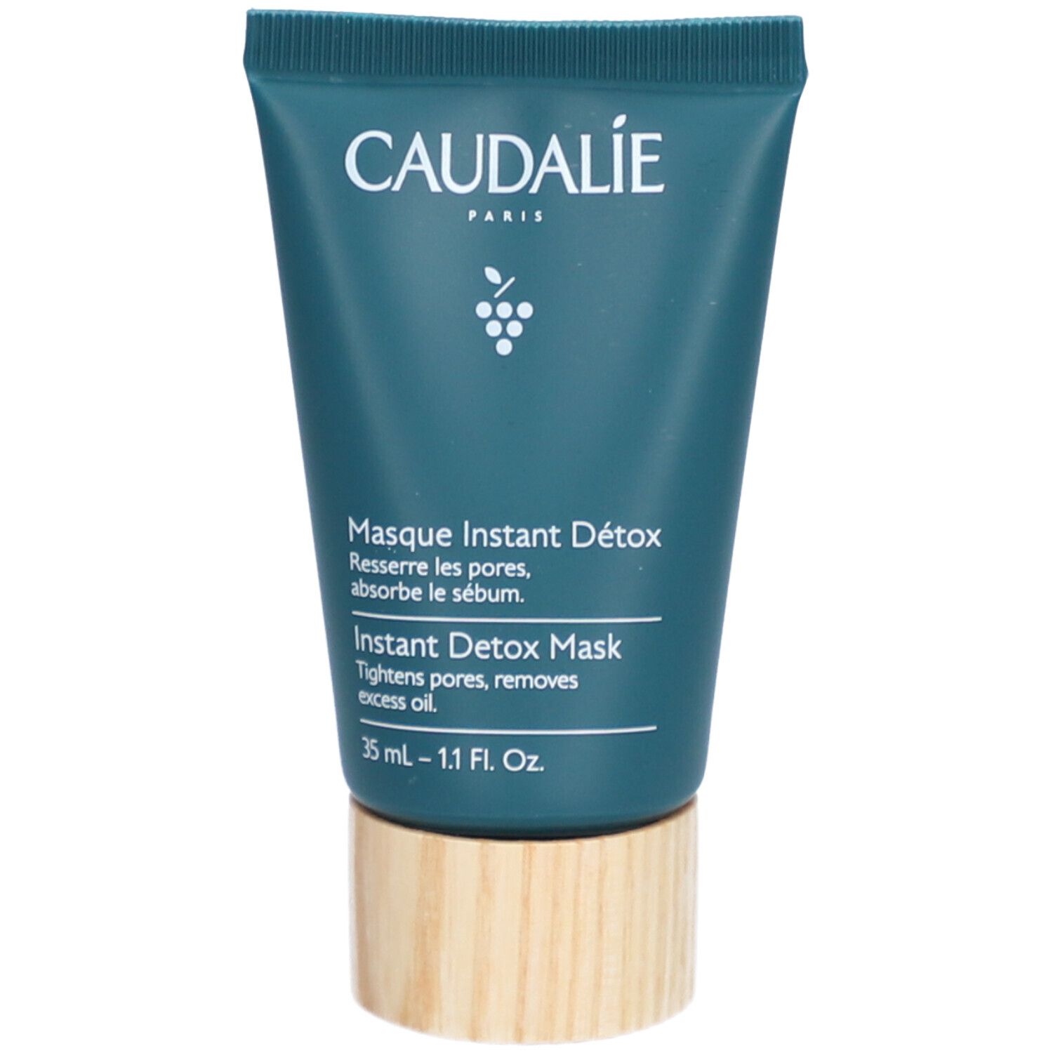 Caudalie Masque Instant Détox Tube. Blaugrüner Tubenbehälter mit weißem Schriftzug. Holzfarbener Boden.