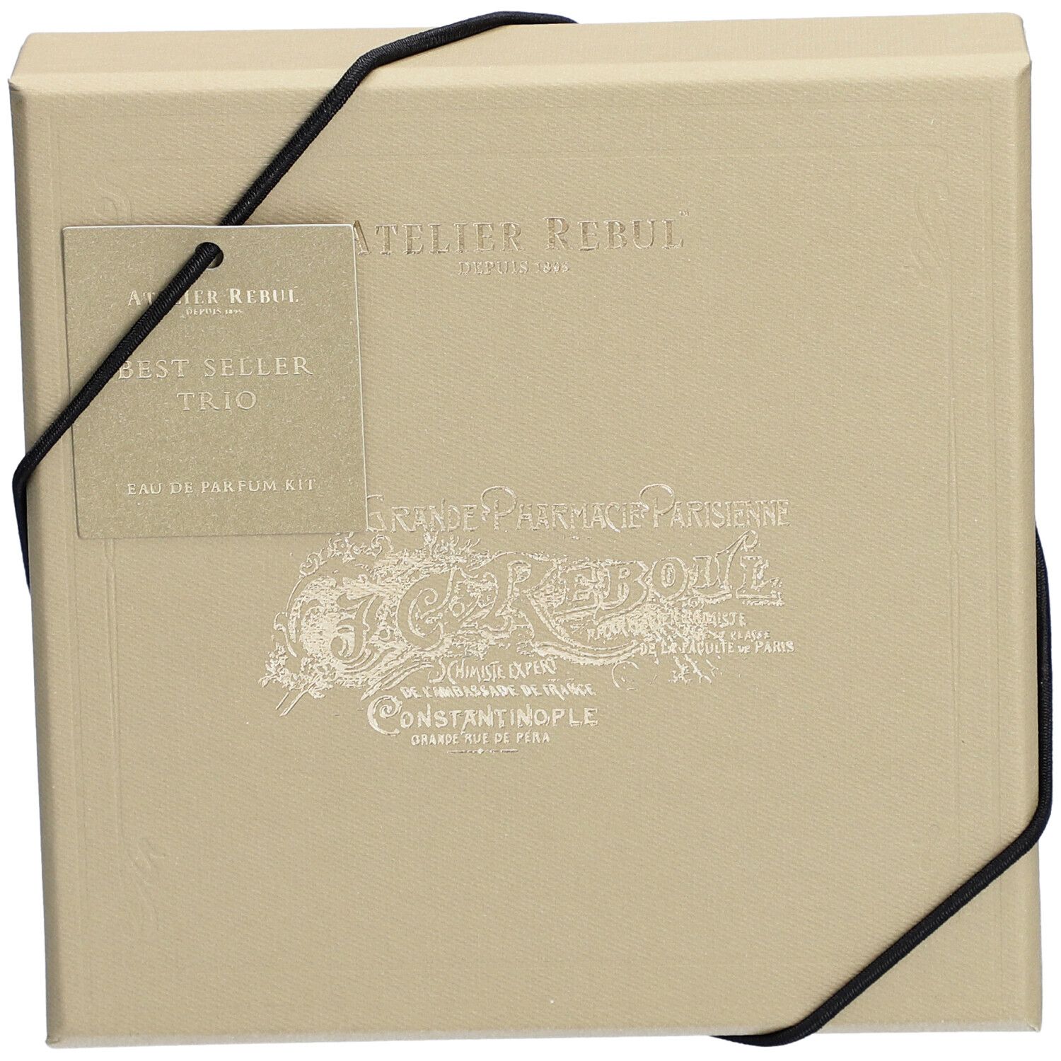 Coffret beige avec élastique noir. Étiquette : Atelier Rebul, Best Seller Trio, Eau de Parfum Kit.