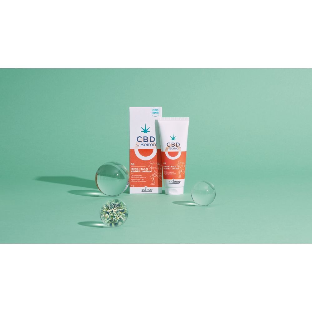 CBD by Boiron Gel Repare & Relaxe, tube en verpakking. Groene achtergrond. Glazen objecten.