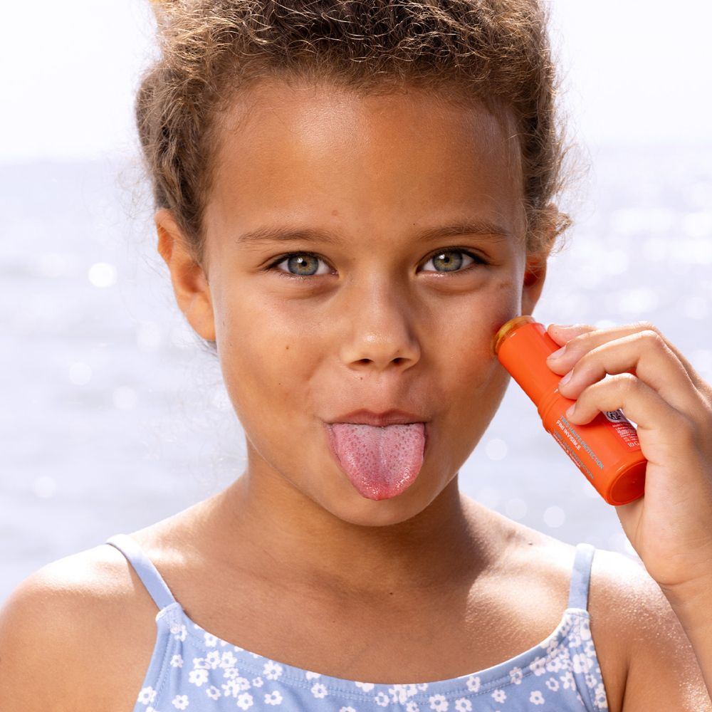 Enfant appliquant SVR Easy Stick SPF50+ sur la joue.