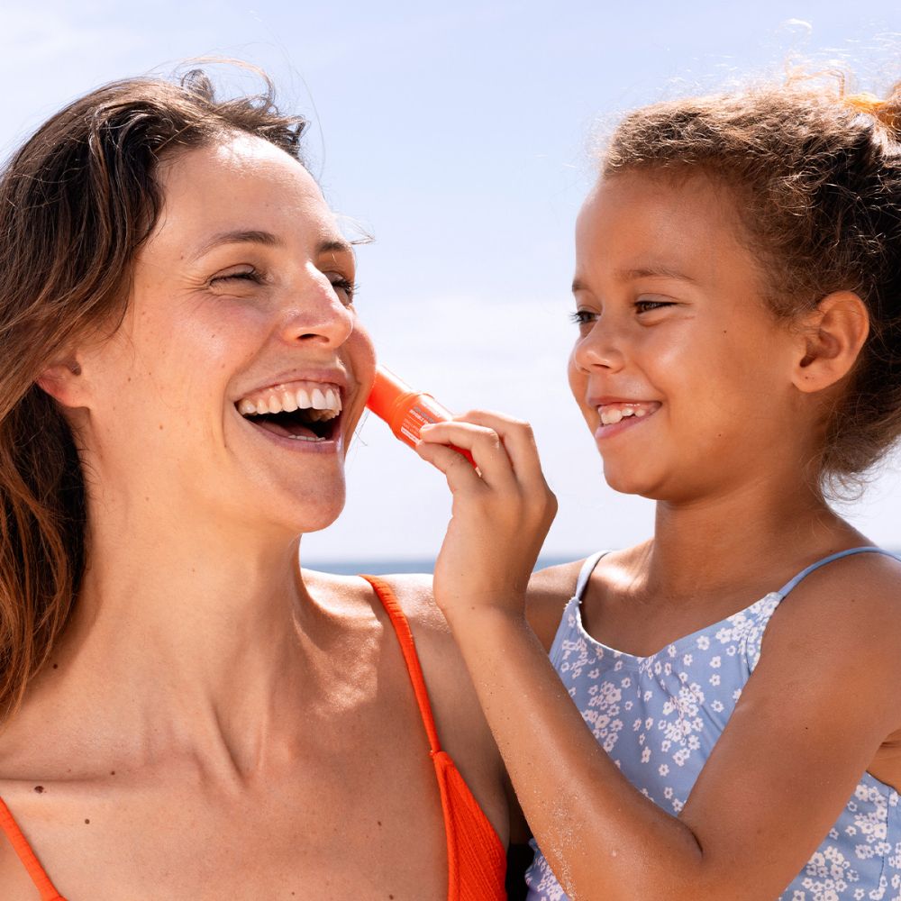 Femme et enfant appliquant SVR Easy Stick SPF50+ sur la joue.