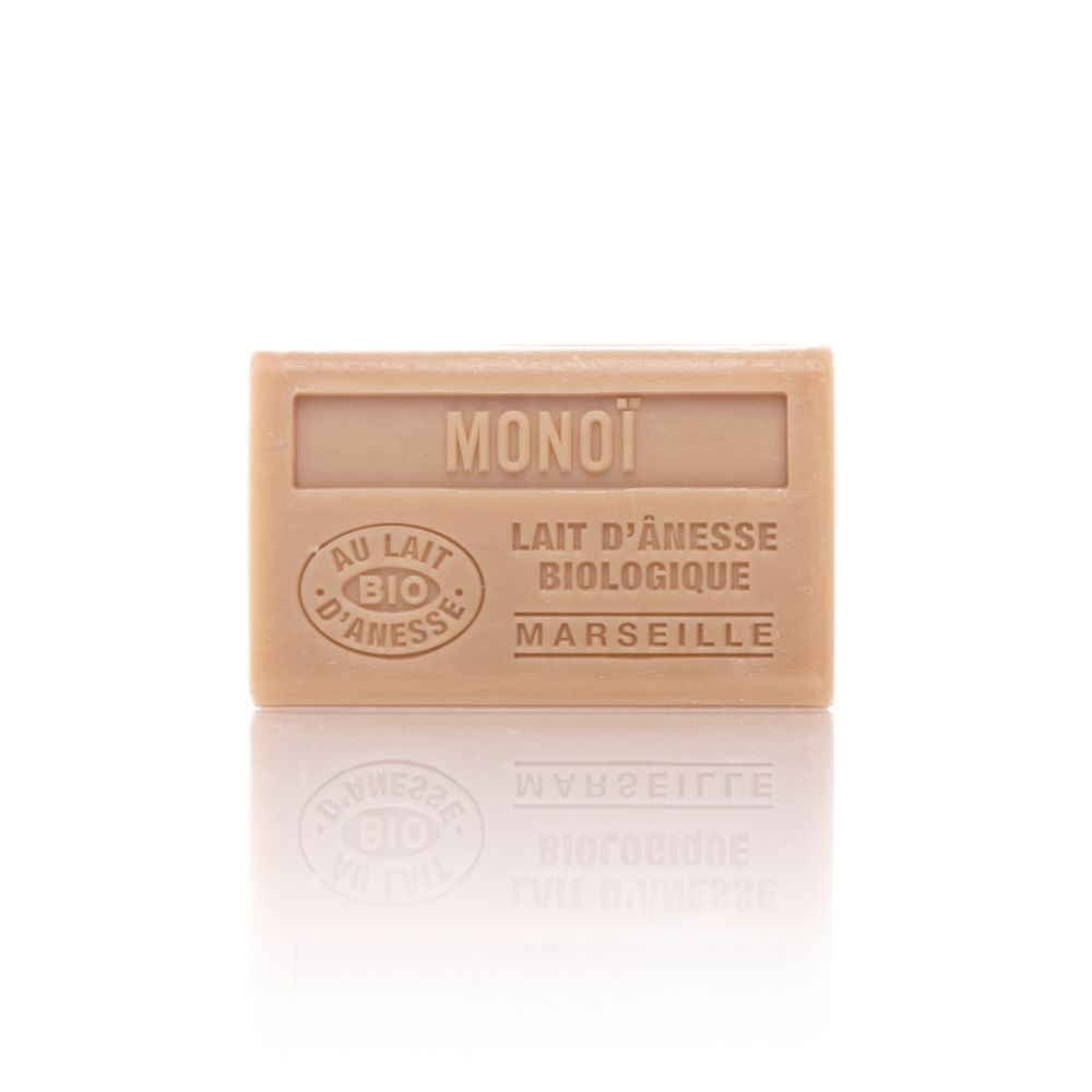 Rechthoekige zeep met opdruk "MONOI", "AU LAIT BIO D'ANESSE" en "MARSEILLE". Lichte kleur, bio-certificering.