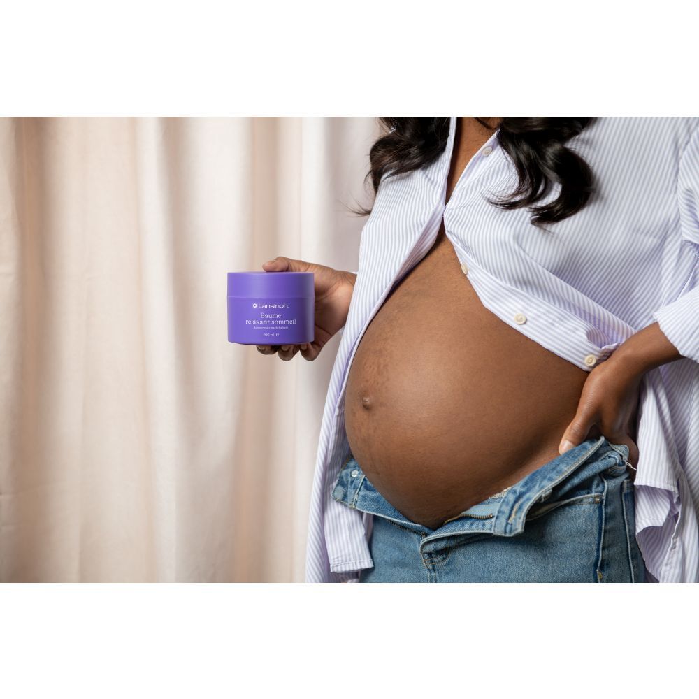 Femme enceinte tenant un pot violet. Texte: Lansinoh, Baume relaxant sommeil, 200 ml.