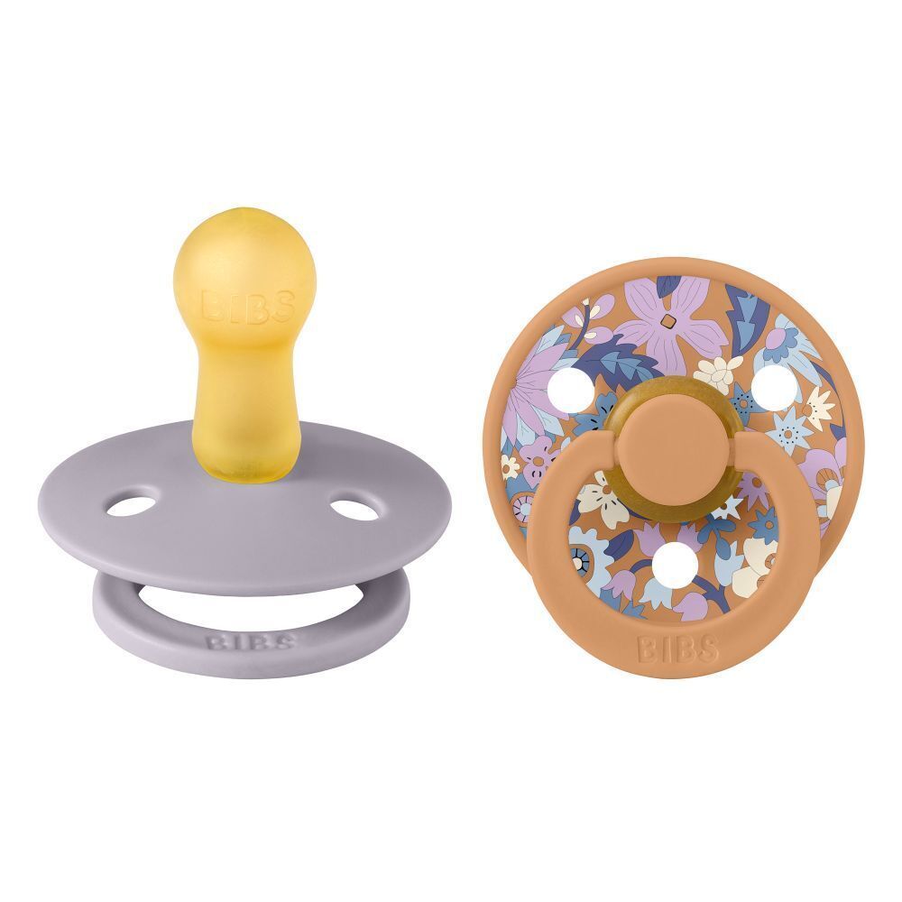 Deux sucettes BIBS®. Une jaune, une marron à motifs floraux. Les deux avec le logo BIBS®.