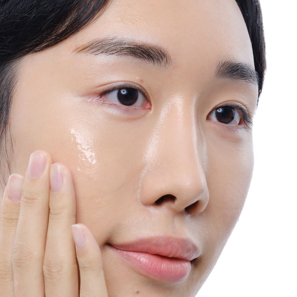 Visage d'une personne. Peau avec liquide clair appliqué. Mains touchant le visage.