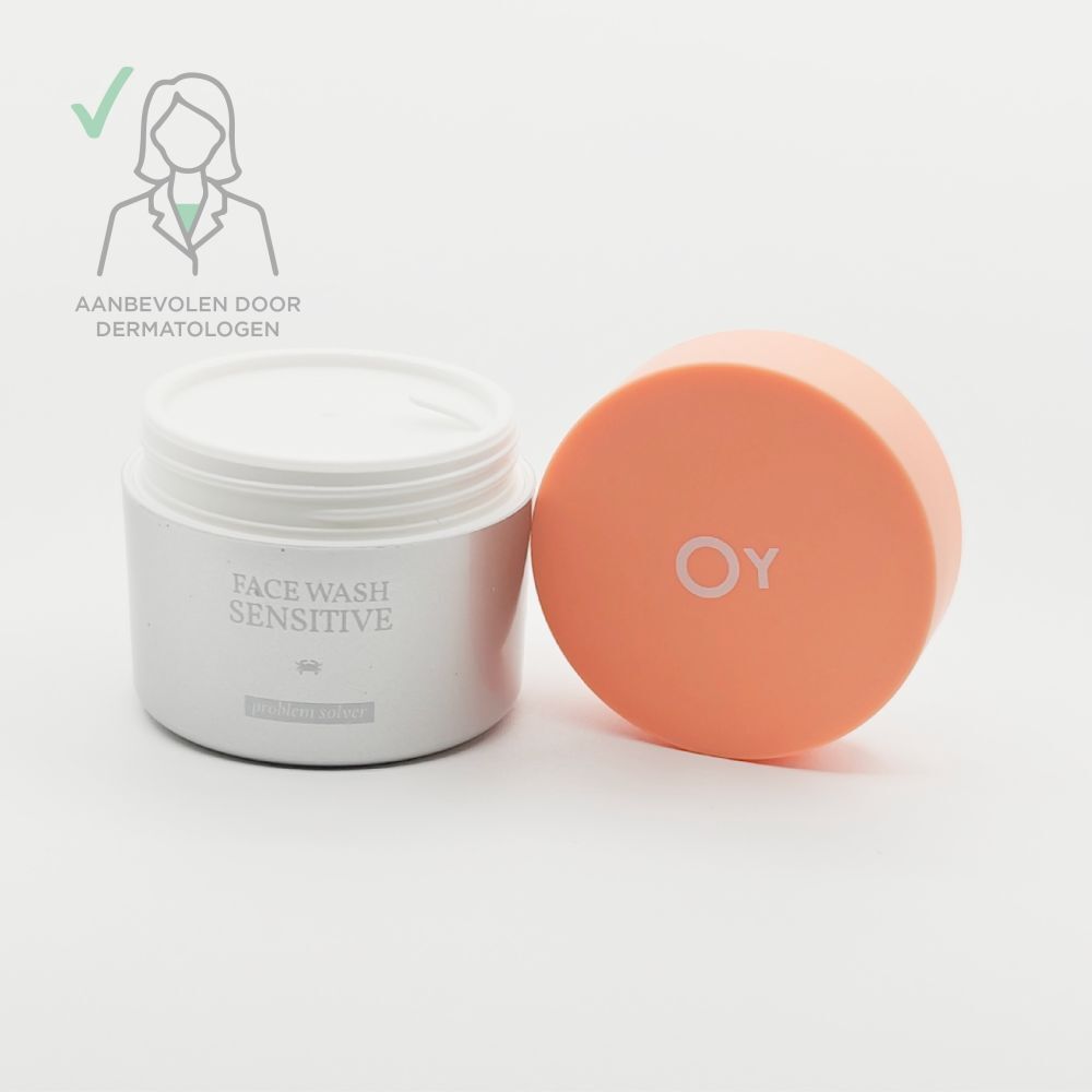 Open crèmepot met oranje deksel ernaast. "FACE WASH SENSITIVE" staat op de pot.