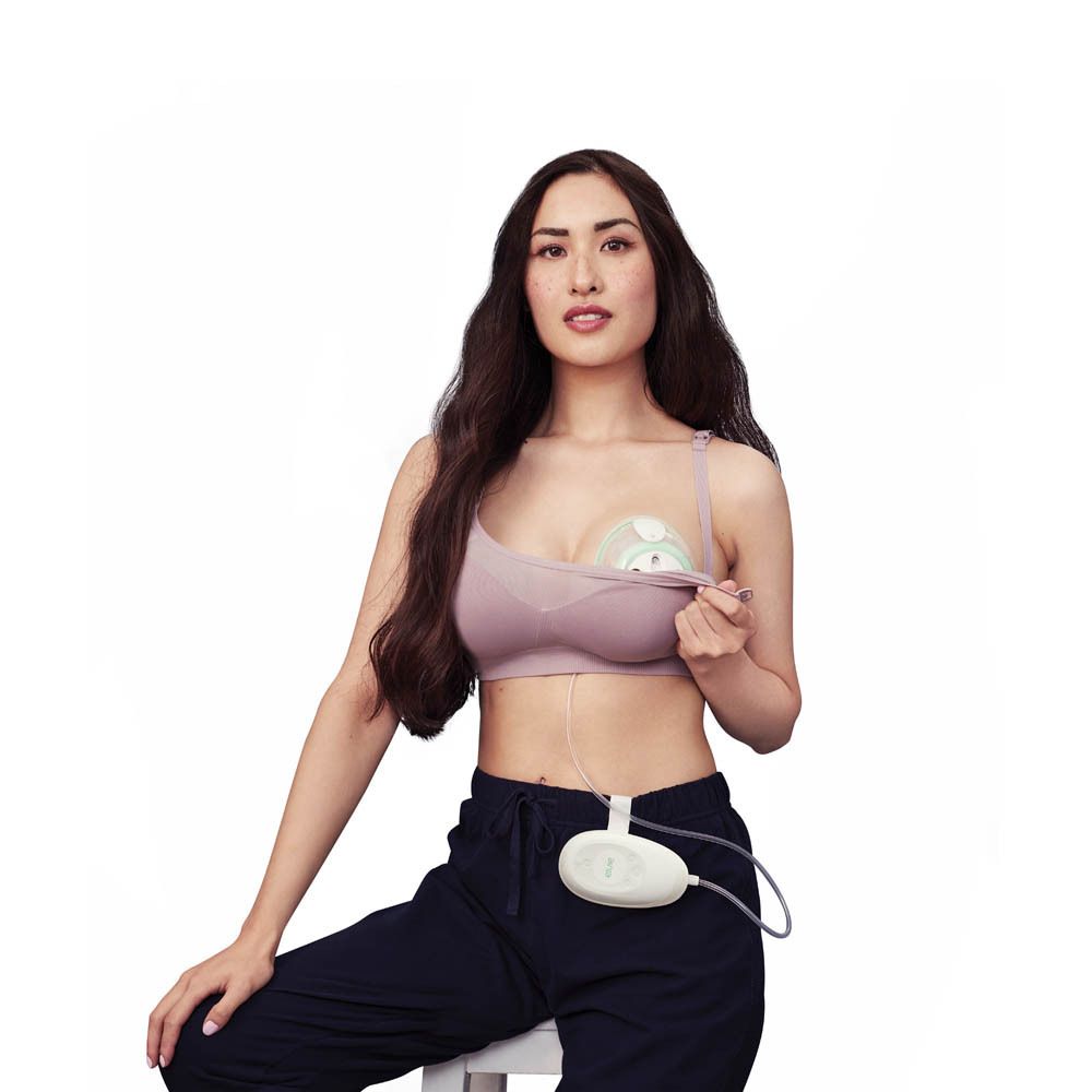 Femme avec pompe mammaire électrique Elvie Stride. Pompe dans le soutien-gorge, unité de contrôle sur le corps.
