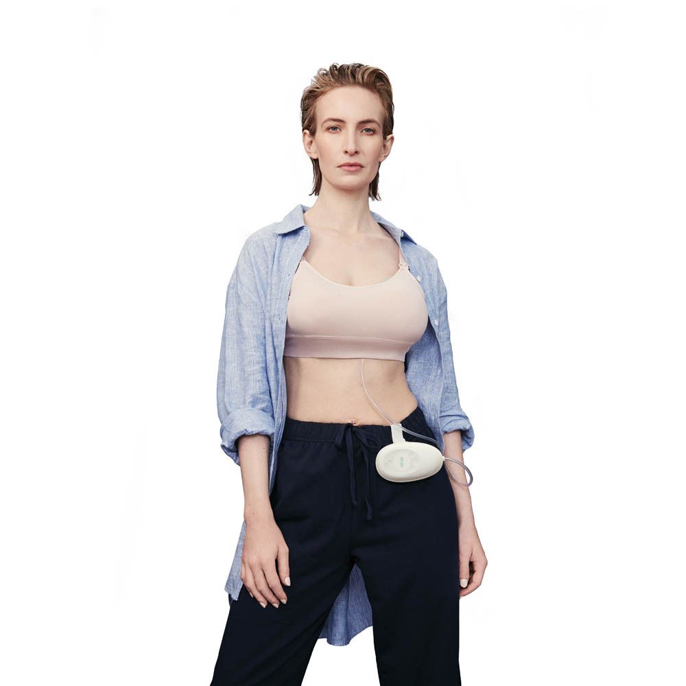 Femme avec pompe mammaire électrique Elvie Stride. Pompe dans le soutien-gorge, unité de contrôle sur le corps.