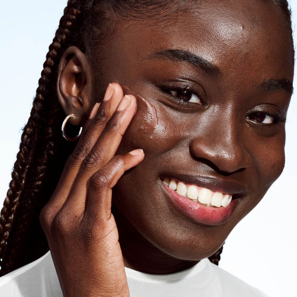 Femme appliquant du maquillage. Gros plan sur le visage. Application visible. Peau foncée.
