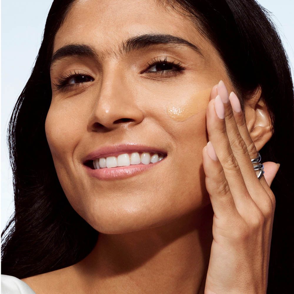 Femme appliquant du fond de teint. Application sur la joue. Peau moyenne.